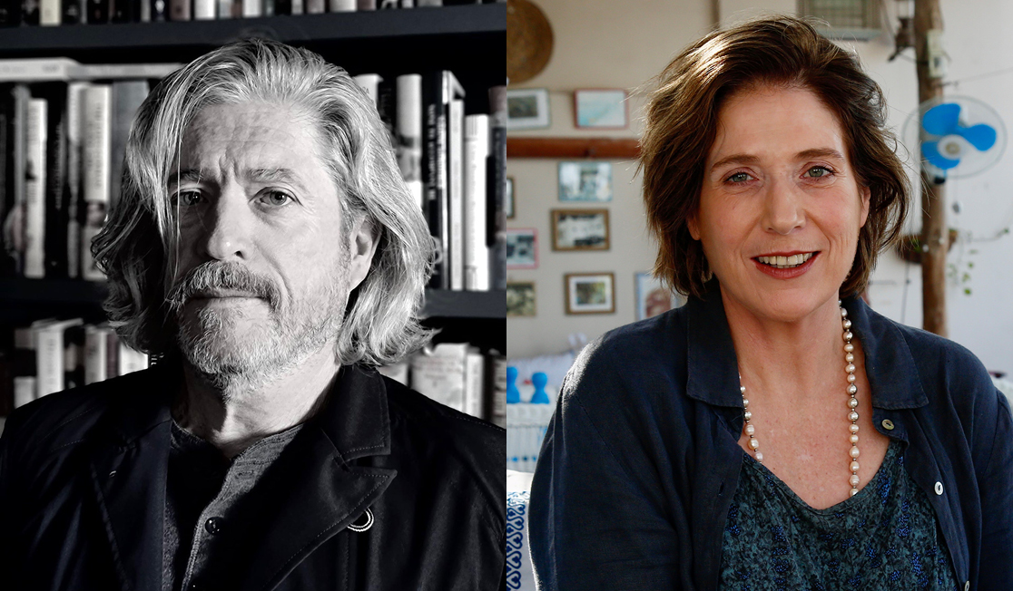 Peter Godwin is smiling in front of a bookshelf. He has long grey hair and a beard and wears a dark jacket. Georgina Godwin has brown hair and wears a navy shirt and a necklace. Georgina is smiling and there are framed pictures on the wall beind.