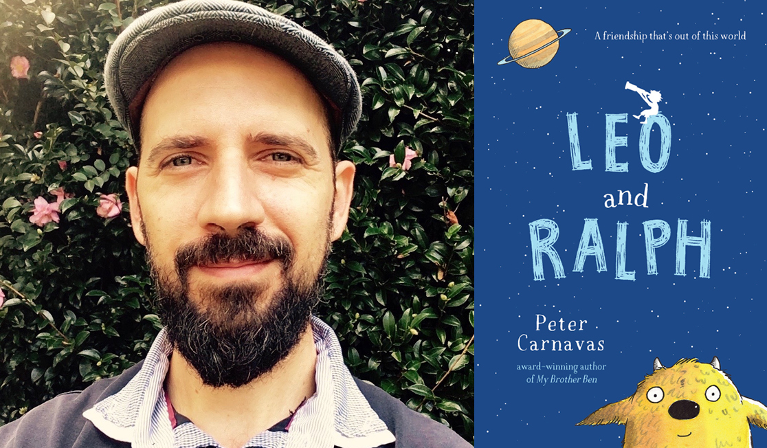 Peter Carnavas stands in front of greenery. Peter has a dark beard, wears a grey hat and is smiling.