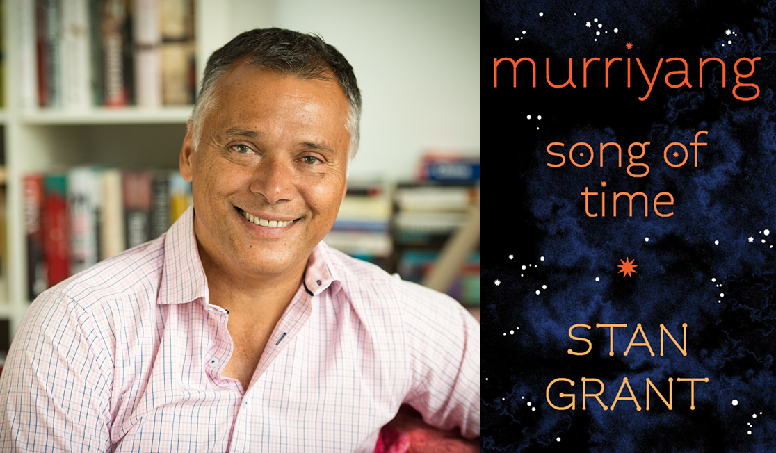Stan Grant wears a pink shirt and smiles. He has short hair and sits in front of stacks of books. The book jacket shows an illustration of a cloudy sky with constellations of stars.