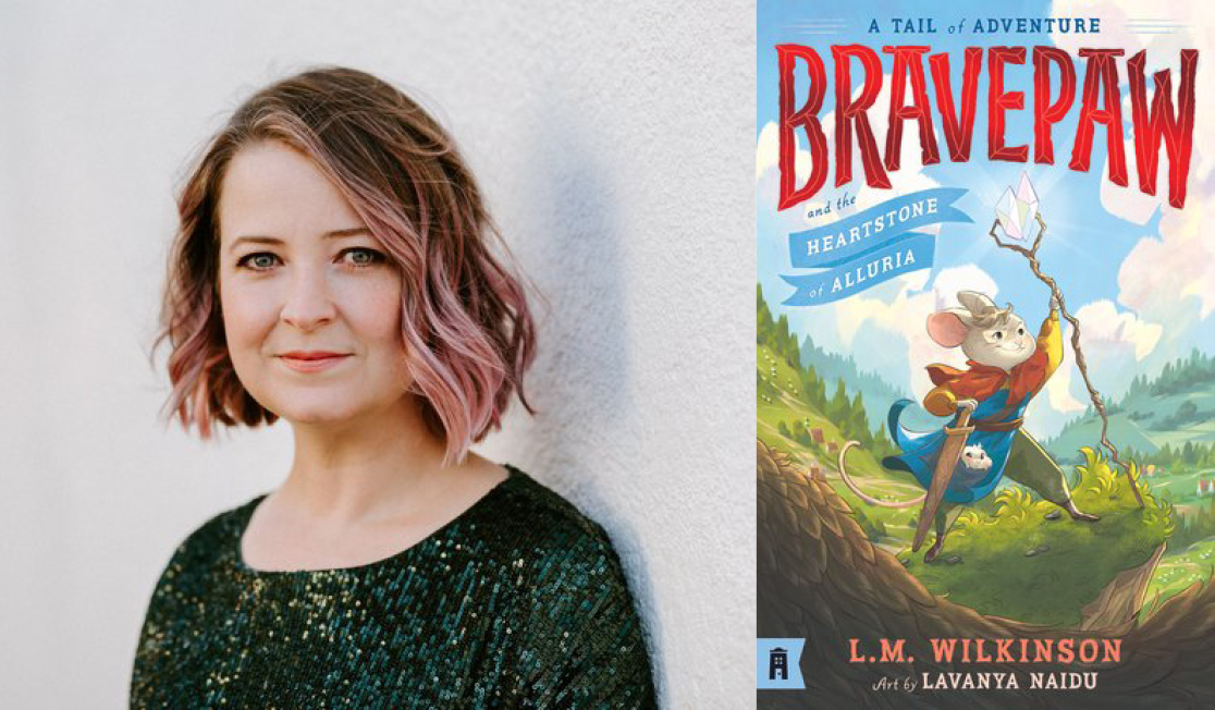 Lili Wilkinson wears a dark top and has shoulder length hair. Lili stands in front of a white wall and is smiling.