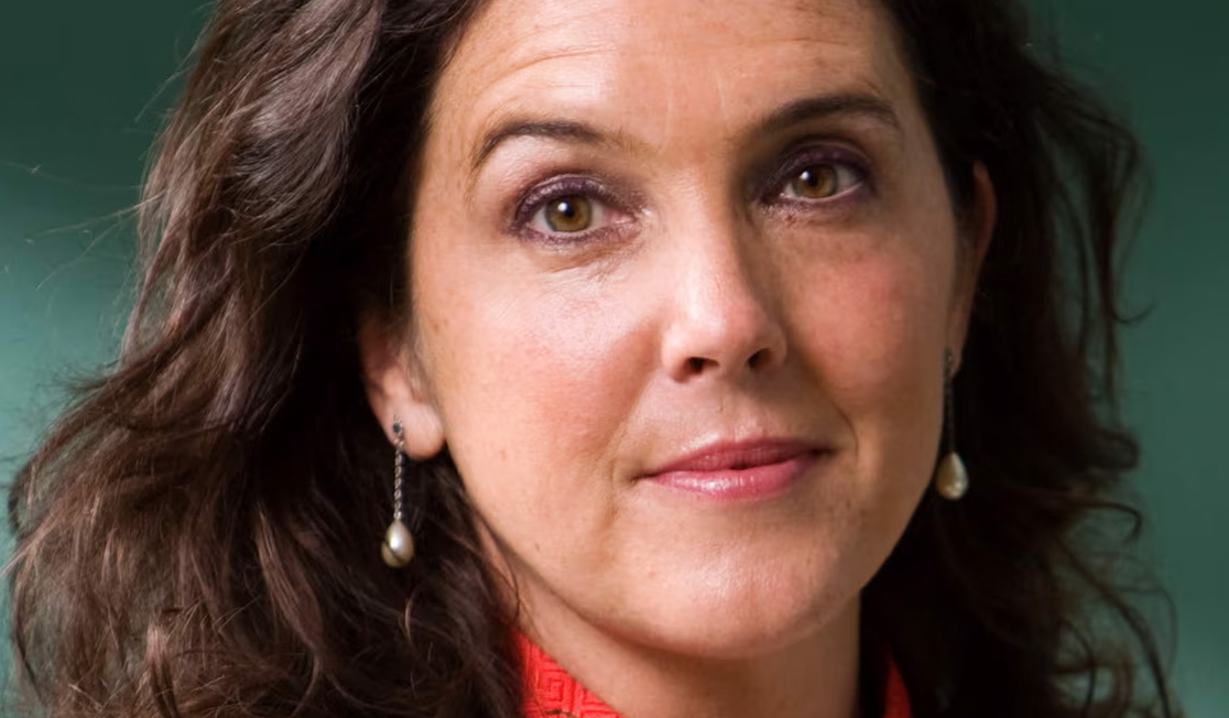Bettany Hughes wears a shirt with a red collar and looks directly at the camera