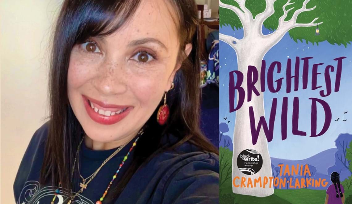Tania Crampton-Larking wears a dark top and necklaces. Tania has red earrings on and brown hair with a fringe. Tania is smiling.