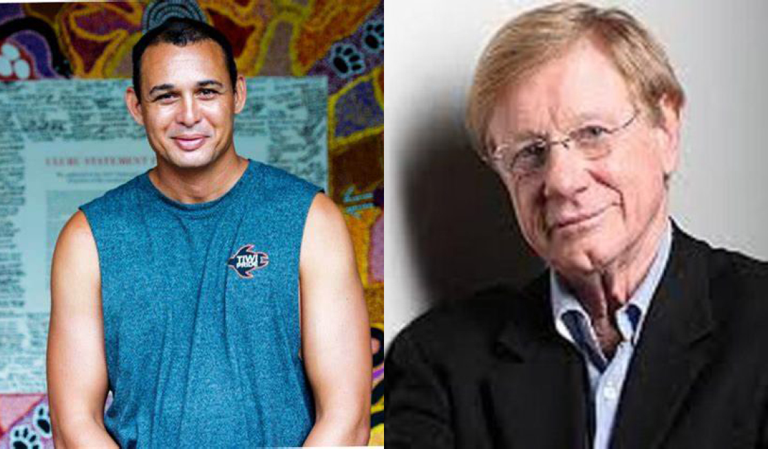 Thomas Mayo stands in front of a colourful wall wearing a blue tank top.