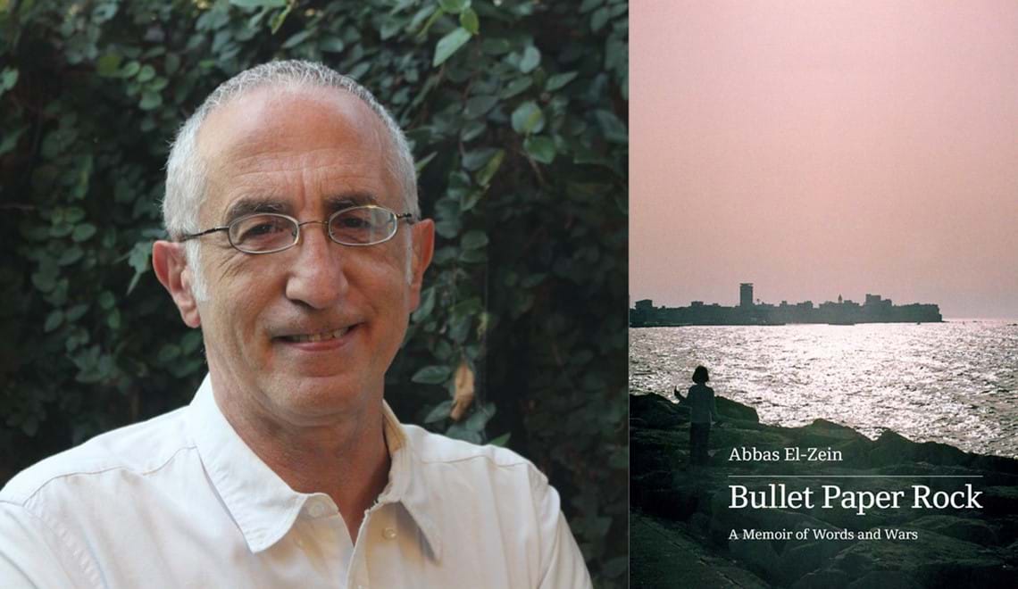 Abbas El-Zein stands in front of green foliage. Abbas wears a white shirt and glasses and has short grey hair. Abbas is smiling.